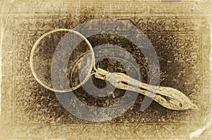 Macro image of magnifying glass over antique black cover. retro filtered image, old style photo