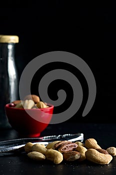 Macro Image of Mixed Nuts with Red Bowl Nutcracker Tool and Glass Bottle