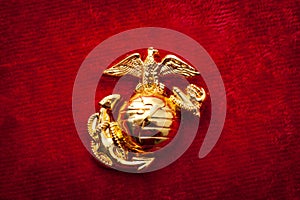 Macro image of the US Marine Corps emblem on red velvet as background and a grungy aesthetic. Semper fidelis or Semper Fi is Latin photo