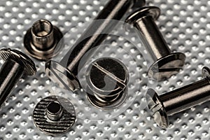 A Macro image of various sized Chicago Screws or Barrel Bolts of varying lengths on a stainless steel industrial background