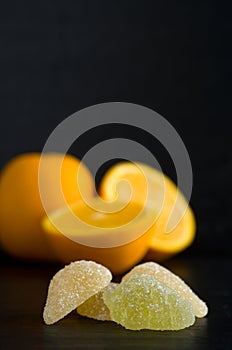 Macro of Jelly Orange and Lemon Candies with Oranges in Background