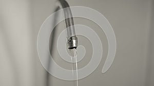 Macro, a jet of water flows from a metal kitchen faucet and turns into droplets.