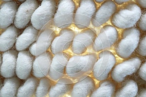 Macro of large white woven background with yellow light showing though woven fibers inbetween poofs
