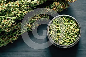 Macro of marijuana with trichomes and crushed weed in a grinder for chopping a canapis on a black table