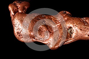 Macro mineral stone of a copper nugget on a microcline on a black background