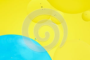 Macro photo with circles oil droplets water surface. Abstract blue and yellow background with oil bubbles.