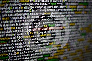 Macro photo of computer screen with program source code and highlighted ERASE YOUR HARD DRIVE inscription in the middle