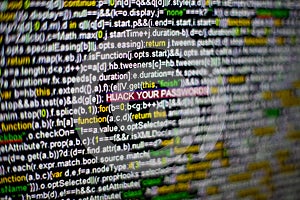 Macro photo of computer screen with program source code and highlighted HIJACK YOUR PASSWORDS inscription in the middle