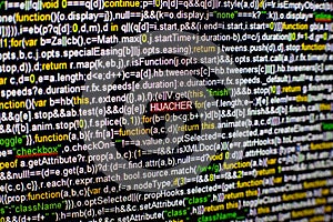 Macro photo of computer screen with program source code and highlighted HIJACKER inscription in the middle. Script on