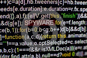 Macro photo of computer screen with program source code and highlighted SPYWARE inscription in the middle. Script on the