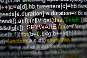 Macro photo of computer screen with program source code and highlighted SPYWARE inscription in the middle. Script on the