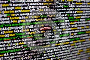 Macro photo of computer screen with program source code and highlighted SPYWARE inscription in the middle. Script on the