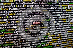 Macro photo of computer screen with program source code and highlighted TROJAN inscription in the middle. Script on the