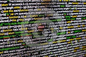 Macro photo of computer screen with program source code and highlighted VIRUS inscription in the middle. Script on the