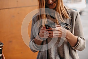 macro photo of a girl drinking coffee and using a cell phone during a break from work.