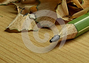 Macro photo of a green pencil with pencil shavings in the background