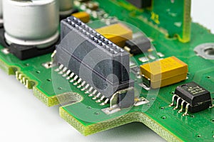 Macro photo of the integrated circuit on a green printed circuit board, visible resistors, capacitors and multi-pin cable connecti