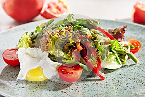 Macro Photo of mixed salad with poached egg, sliced sweet bell pepper, fresh lettuce leaves and cherry tomatoes. Restaurant starte