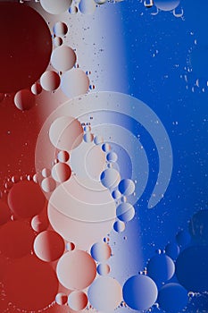 Macro photo of mixing oil and water. Oil droplets above a beautiful coloured abstract background creating circles and ovals.