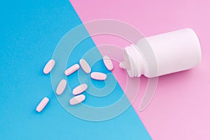 Macro photo pills that pour out of a white bottle on a pastel colored background. Pills on pink and blue background