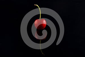 Macro photo of red cherry with water drops on black background. Selective focus.