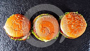 macro photo of three hamburgers_on black kitchen granite surface top view