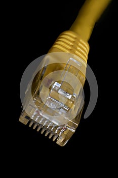 Macro photo of a yellow 8 pin ethernet plug on black background