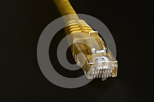 Macro photo of a yellow 8 pin ethernet plug on black background