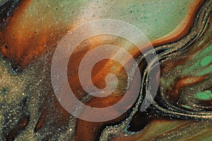 Macro photograph of earthtone colored abstract background featuring swirling black and gold.
