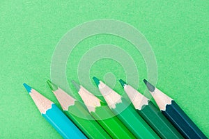 Macro photograph of several pencils of green color on a paper background
