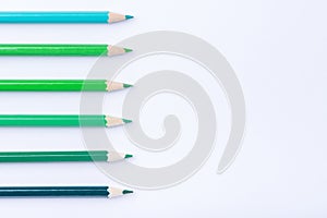 Macro photograph of several pencils of green color on a white ba