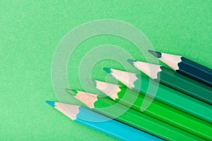 Macro photograph of several pencils of green color on a paper ba