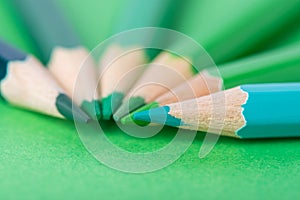 Macro photograph of several pencils of green color on a paper background