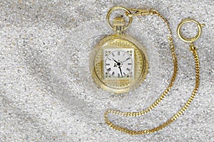 Macro photography of a gold pocket watch on sand