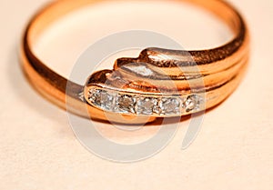 Macro photography of a gold ring with several cubic Zirconia on a light background