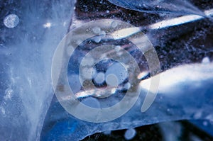 Macro photography of natural ice. Bubbles of gas inside crystals. Cracks and optical effects. Abstract textures.