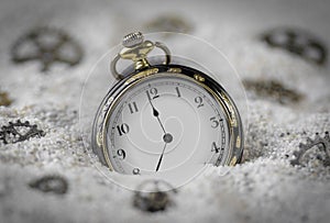 Macro photography of a old black and gold pocket watch on sand