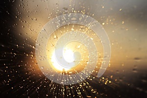 Macro photography of rain drops on the glass on a blurry background of the setting sun. Texture in dark and orange tones. Blur wit