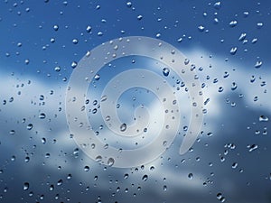 Macro photography of rain drops on the glass on a blurry background of the skyy. Texture in dark and orange tones.