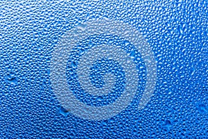 Macro photography of water drops on glass window blue background after the rain.