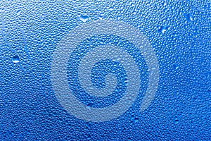 Macro photography of water drops on glass window blue background after the rain.