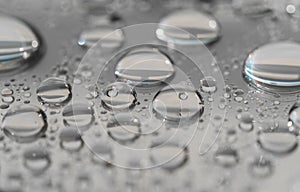 Macro photography of water drops on a mirror reflective surface.