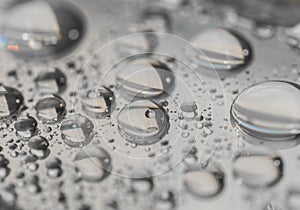 Macro photography of water drops on a mirror reflective surface.