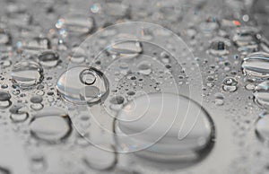 Macro photography of water drops on a mirror reflective surface.