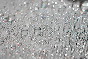 Macro photography of water drops on a mirror reflective surface.