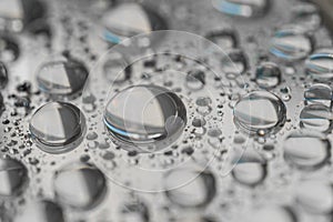 Macro photography of water drops on a mirror reflective surface.