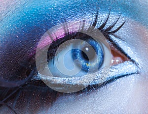 Macro picture of blue woman eye with multicolor make up. Looking