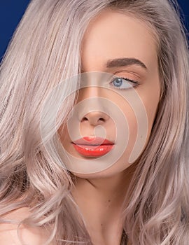 Macro of Platinum Blonde Hair Woman With Blue Eyes and Augmented Lips, Painted With Coral Lipstick, Looking Away