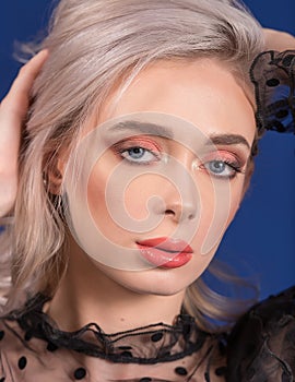 Macro of Platinum Blonde Hair Woman With Blue Eyes and Augmented Lips, Painted With Coral Lipstick, Playing with Her Hair