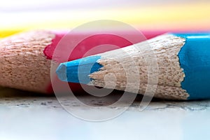 A macro portrait of a wooden blue color pencil lying in front of other colored pencils. It is used, because the tip is blunt, it